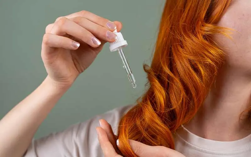 Applying Hair Serum to Red Curls in Close-up | Everything You Need to Know About Hair Gloss Treatment